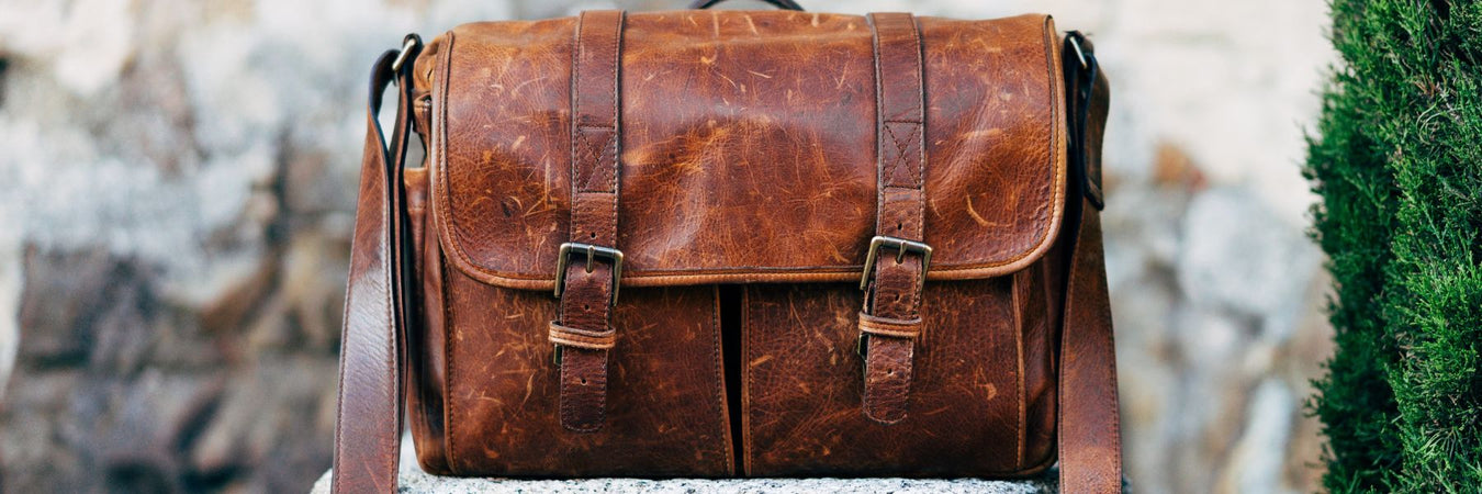 Mens Accessories With Dark Brown Leather Bags On Wooden Table Over